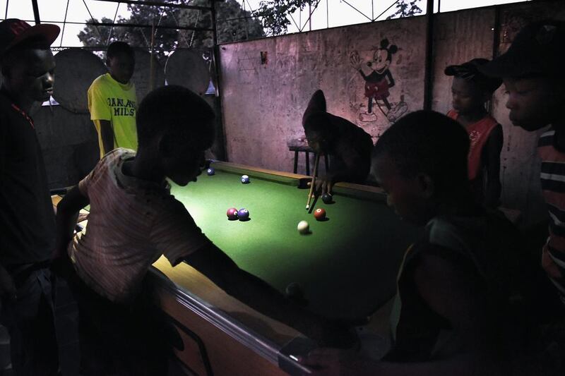Young boys play pool by torchlight in the gathering darkness because electricity is only available for a few hours, usually late at night, in Chitungwiza, Zimbabwe. Mary Turner / Getty Images