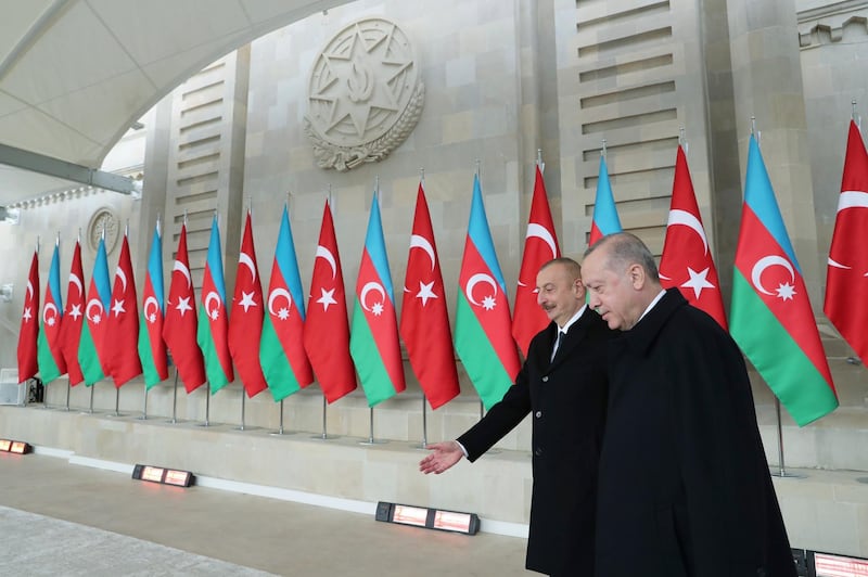 Azerbaijan's President Ilham Aliyev welcomes Turkish President Recep Tayyip Erdogan, right, as they attend a parade in the Azerbaijani capital Baku on December 10, 2020 to celebration the end of fighting in Nagorno-Karabakh. Turkish Presidency via AP