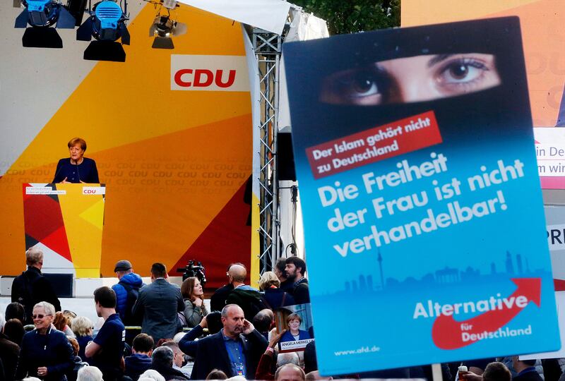 German Chancellor Angela Merkel, left, speaks as supporters of the right-wing party Alternative for Germany or AfD hold up a poster during an election campaign in Giessen, central Germany, Thursday, Sept. 21, 2017. The poster reads "Islam is not part of Germany. The freedom of the woman is not negotiable!" (AP Photo/Michael Probst)