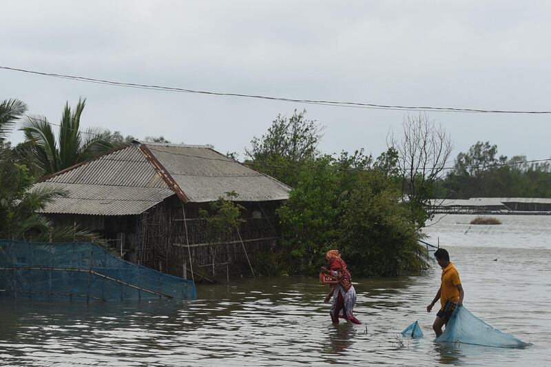 Residents wade through a flooded area after a dam broke following the landfall of cyclone Amphan in Shyamnagar.  At least 84 people died as the fiercest cyclone to hit parts of Bangladesh and eastern India this century sent trees flying and flattened houses, with millions crammed into shelters despite the risk of coronavirus.  AFP