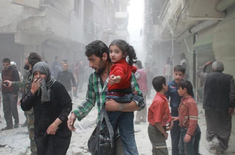 A Syrian man carrying a child makes his way amid rubble following reported air strikes by government forces in Aleppo. Baraa Al Halabi / AFP Photo