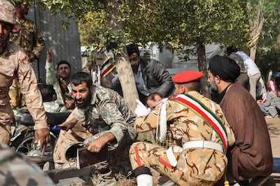 This picture taken on September 22, 2018 in the southwestern Iranian city of Ahvaz shows soldiers and a Shiite Muslim cleric (R) sitting close to the ground seeking cover at the scene of an attack on a military parade that was marking the anniversary of the outbreak of its devastating 1980-1988 war with Saddam Hussein's Iraq. At least eight troops were killed on September 22 in an attack on a military parade in the southwestern province of  Khuzestan, the province's deputy governor Ali-Hossein Hosseinzadeh said. / AFP / ISNA / BEHRAD GHASEMI
