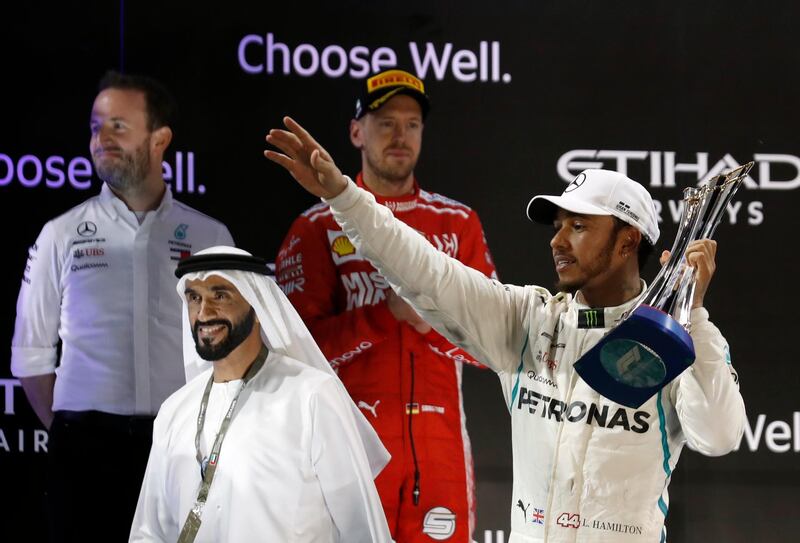 Lewis Hamilton holds his trophy on the podium. AP Photo