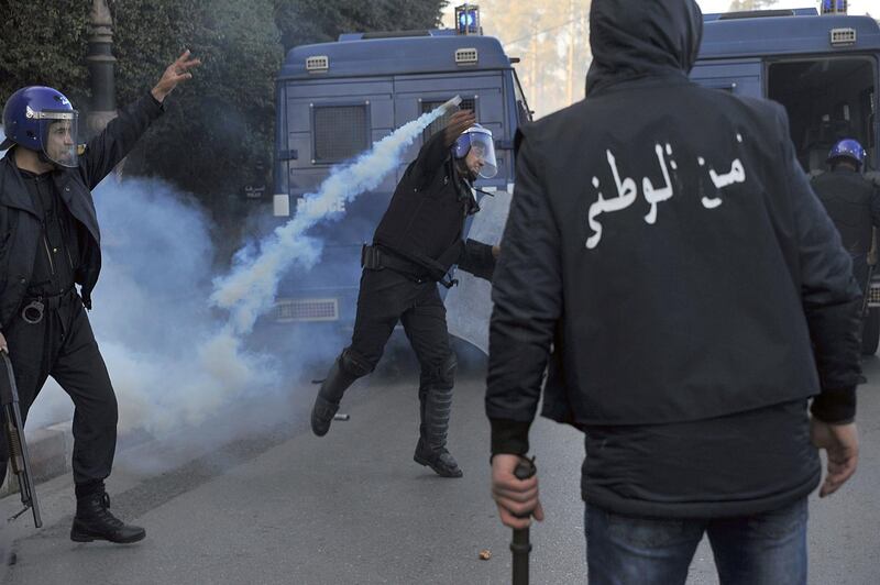 A police officer throws back a tear gas canister during scuffles with protesters. AP