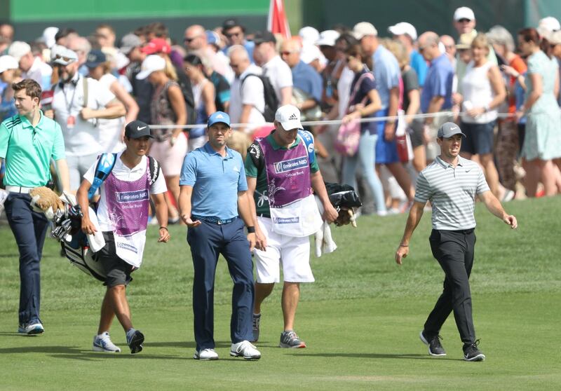DUBAI, UNITED ARAB EMIRATES - JANUARY 25:  Rory McIlroy of Northern Ireland and Sergio Garcia walk down the fairway on the par 4, ninth hole followed by large crowds during the first round of the Omega Dubai Desert Classic on the Majlis Course at Emirates Golf Club on January 25, 2018 in Dubai, United Arab Emirates.  (Photo by David Cannon/Getty Images)