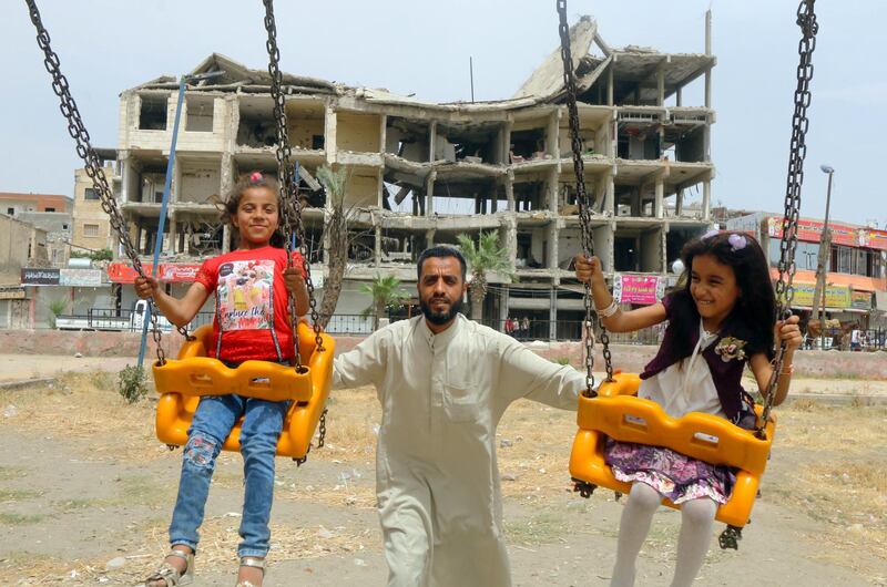 Girls ride on swings near a damaged building during the first day of Eid Al Fitr in Raqqa, Syria.