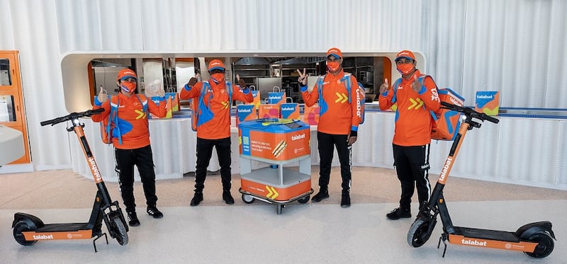 Talabat riders with e-scooters and 'tala-bots', which showcase what the future of food delivery might look like.