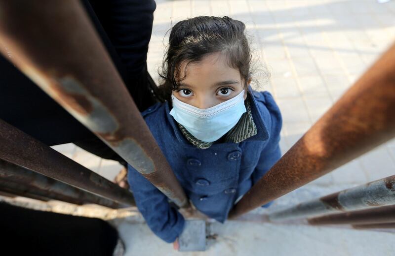 A Palestinian girl looks through a gate fence as she waits to leave the Rafah border crossing with Egypt, which was reopened partially amid the spread of the coronavirus disease, in the southern Gaza Strip. Reuters