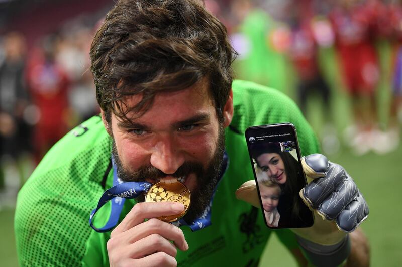 Alisson takes a playful bite out of his medal in Madrid. Getty