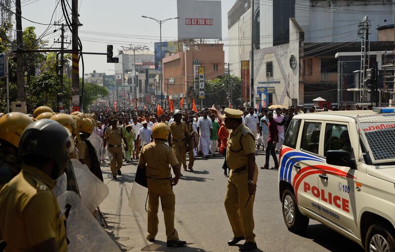 Policemen stand guard during a march by Bharatiya Janata Party activists as part of a strike call by Sabarimala Karma Samithi, an umbrella organization of Hindu groups, in Thiruvananthapuram, capital of the southern Indian state of Kerala, Thursday, Jan. 3, 2019. Hindu hard-liners shut shops and businesses and clashed with police in the state Thursday to protest the entry of two women in one of India's largest Hindu pilgrimage sites. (AP Photo/R.S. Iyer)