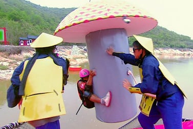 A Takeshi's Castle contestant hangs onto a giant inflatable mushroom as two of the show's characters try to dislodge him. Takeshi's Castle