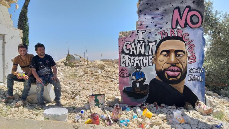 Aziz Asmar, right, and Anis Hamdoun, sitting in front of mural they drew of George Floyd in Idlib, Syria. Aziz Asmar