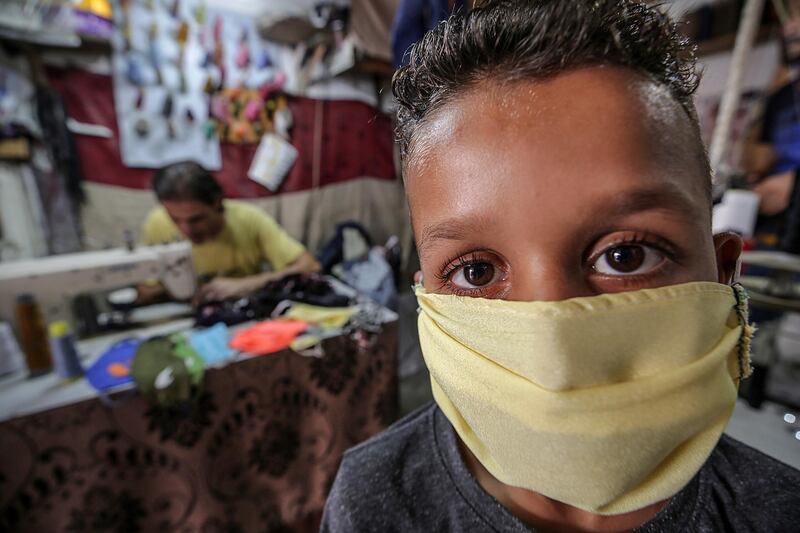 A child poses for a photo with mask made by Mohammed Awadallah, 33, a Palestinian fisherman and tailor in Al Shatea refugee camp in Gaza City. EPA