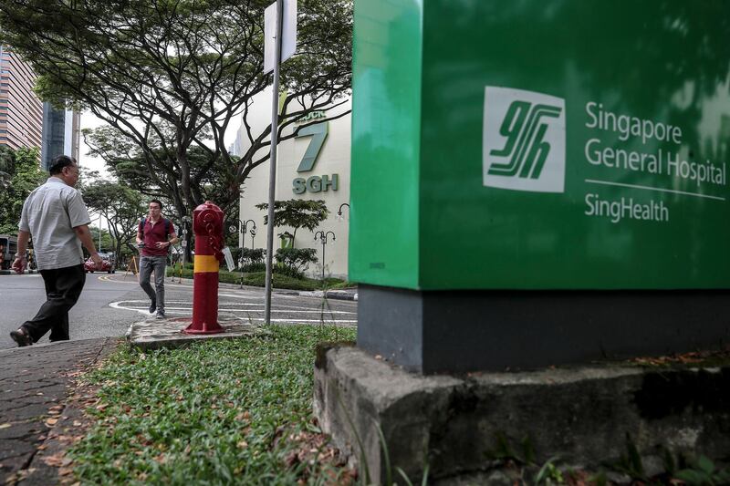 epa06901951 Two men (L) walk past a sign bearing the logo of the  Singapore General Hospital, in Singapore, 21 July 2018. According to media reports, hackers gained access to the health data of about 1.5 million patients who had visited Singhealth hospitals and clinics in Singapore between 2015 and 2018. The data breach was discovered on 04 July and was aimed at uncovering the medical information of Singapore Prime Minister Lee Hsien Loong.  EPA/WALLACE WOON