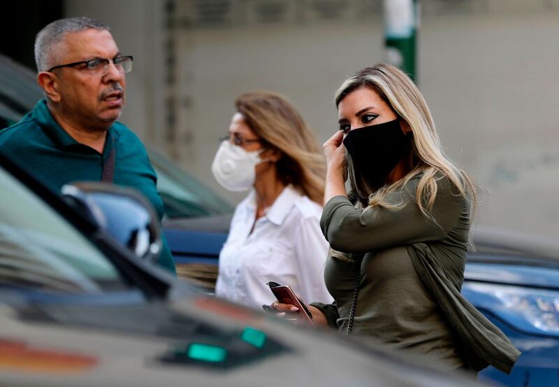 A woman adjusts her mask as she walks along a street in Lebanon's capital Beirut.  AFP