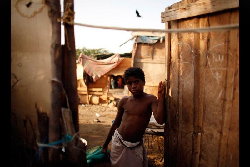 A boy stands at the door of his family's hut.