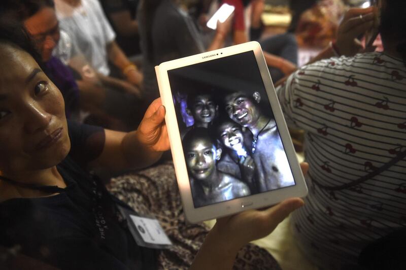 A happy family member shows the latest pictures of the missing boys taken by rescue divers inside Tham Luang cave  when all members of children's football team and their coach were found alive in the cave at Khun Nam Nang Non Forest Park in the Mae Sai district of Chiang Rai province late July 2, 2018. Twelve boys and their football coach trapped in a flooded Thai cave for nine days were "found safe" late July 2, in a miracle rescue after days of painstaking searching by divers. - 
 / AFP / LILLIAN SUWANRUMPHA                 
