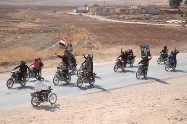 People ride motorcycles and hold a Syrian flag and a portrait of Syrian President Bashar Assad as they welcome Syrian troops. AP