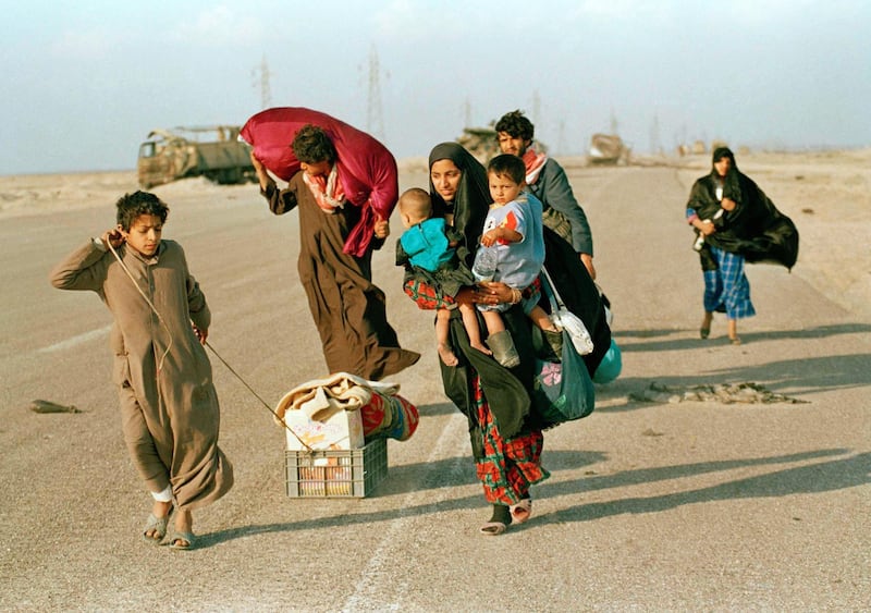 Near the northern Kuwait-Iraq border, a Kuwaiti refugee family heads towards home on March 2, 1991 in Kuwait after being imprisoned in Iraq for a month during the war. They carry what belongings they have left to Kuwait City, 100 miles away. (AP Photo/J. Scott Applewhite)