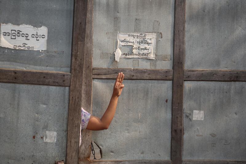 A resident flashes the three-finger salute as demonstrators march during a protest against the military coup in Mandalay. EPA