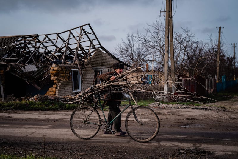 Volodymyr Kovalov, 77, carries tree branches attached to his bike as he collects wood for heating and cooking in Kherson region. AFP