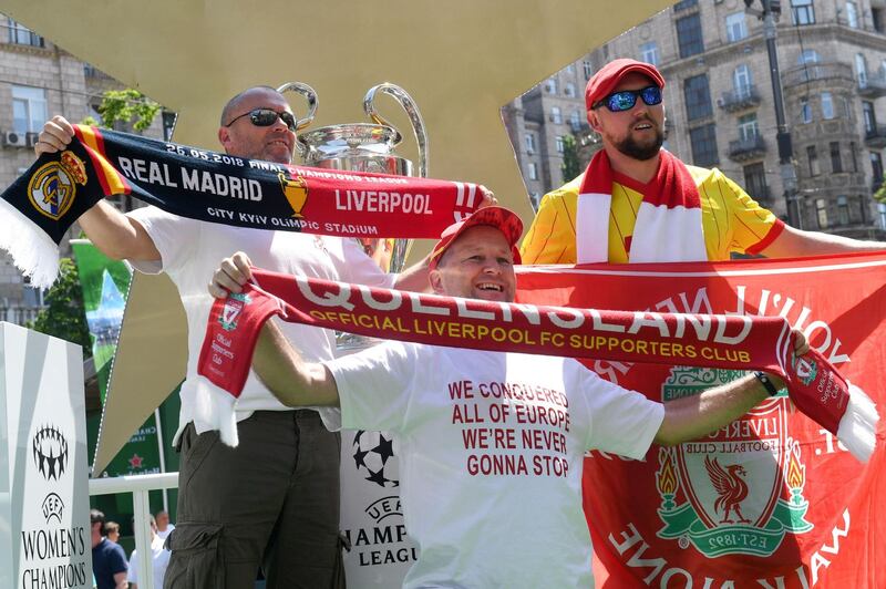 Liverpool fans pose in front of the UEFA Champions League Cup (C) on display at the fan zone in Kiev on May 24, 2018, ahead of the football match between Real Madrid and Liverpool FC next May 26 at the Olimpiyskiy Stadium.  / AFP / Sergei SUPINSKY
