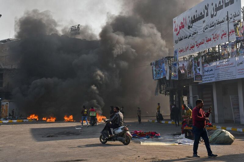 Iraqi protesters are pictured next to burning tyres during clashes with police during anti-government demonstrations in the city of Nasiriyah in the Dhi Qar province in southern Iraq on January 10, 2021.  / AFP / Asaad NIAZI
