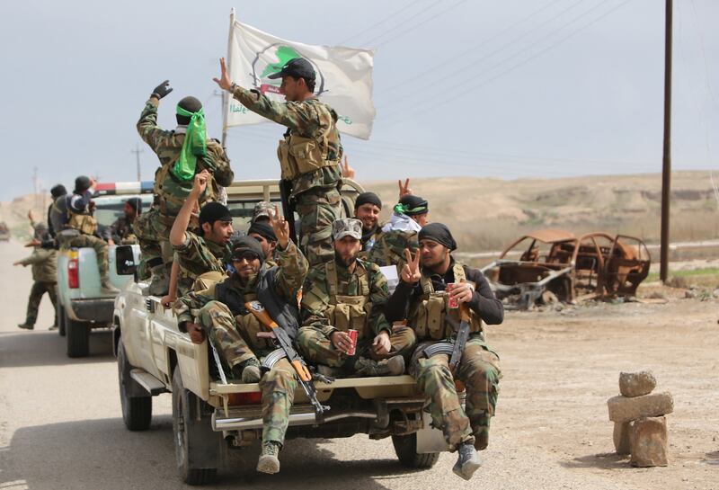 Members of the Iraqi paramilitary Popular Mobilisation units flash the 'V' for victory sign after regaining control of the village of Albu Ajil, near Tikrit, on March 9, 2015.