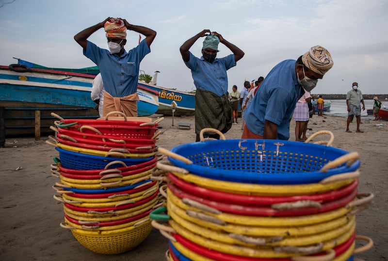 Labourers wearing masks as a precaution against Covid-19 get ready to collect fish from a fishing boat on the Arabian Sea coast in Kochi, Kerala state, India.  AP