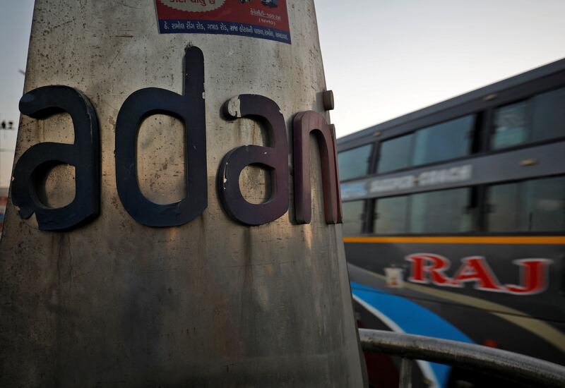 A passenger bus moves past the logo of the Adani Group installed at a roundabout on the ring road in Ahmedabad. Reuters