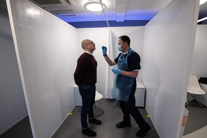 David Spicer (R), of travel services firm Collinson, conducts a novel coronavirus Covid-19 test on a member of staff on the first day of operation of their testing site adjacent to Terminal 1 of Manchester Airport in Manchester, northern England on December 3, 2020.  Collinson are offering paid-for Covid tests at their airport locations in Manchester, East Midlands and London for passengers whose destination country require them. / AFP / OLI SCARFF
