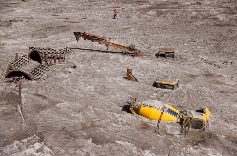 A man walks past construction vehicles submerged in debris caused by flash floods after a lake burst in Rangpo, India, in October. Reuters