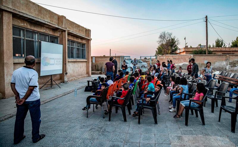 Children attend a film screening as part of the mobile cinema "Komina Film" at a school yard in Shaghir Bazar, in northeastern Syria's Hasakeh province. All photos by AFP