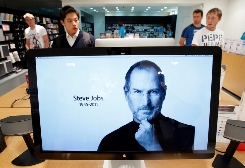Customers look around products behind a computer monitor displaying the obituary of former Apple CEO Steve Jobs at an Apple Store in Seoul October 6, 2011. Apple Inc co-founder and former CEO Steve Jobs died on Wednesday at the age of 56, after a years-long and highly public battle with cancer and other health issues.   REUTERS/Jo Yong-Hak (SOUTH KOREA - Tags: BUSINESS OBITUARY SCIENCE TECHNOLOGY) *** Local Caption ***  SEO103_APPLE-JOBS_1006_11.JPG