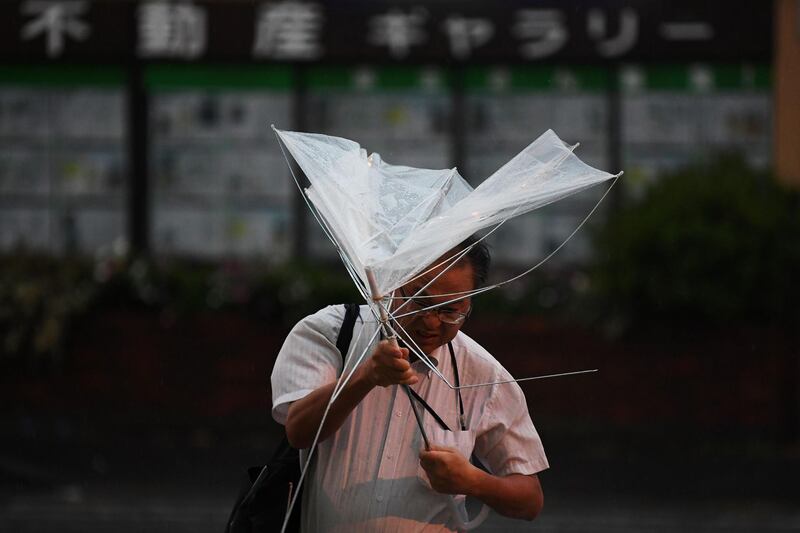 A man with an umbrella crosses a street early morning under the rain as a typhoon hits Tokyo on September 9, 2019. A strong typhoon that could bring record winds and rain was poised to make a direct hit on Tokyo later September 8, as authorities issued evacuation warnings amid a risk of high waves, landslides and flooding. / AFP / Charly TRIBALLEAU
