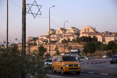 A metal Star of David is seen attached to a utility post by a busy traffic circle that leads to Abu Dis, Azaria and the Jewish settlement of Qadar which is within the contested settlement of  Maale Adumim's boundaries which is seen in the background. Palestinian and Israeli plated cars are seen on the road .(Photo by Heidi Levine for The National )
