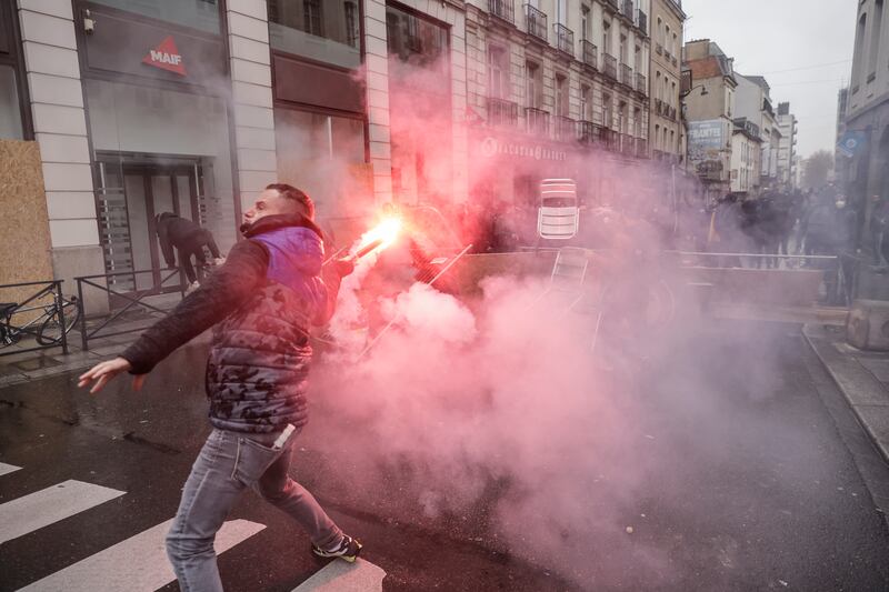 A man throws a flare towards riot police in Rennes, as protests continue across France over pension reforms and the rising cost of living. AP