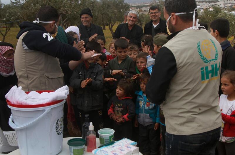 Aid workers from Turkish humanitarian group IHH show Syrian children how to properly wash their hands, at a camp for internally displaced persons in norther Syria, on Monday, April 6, 2020. IHH via AP