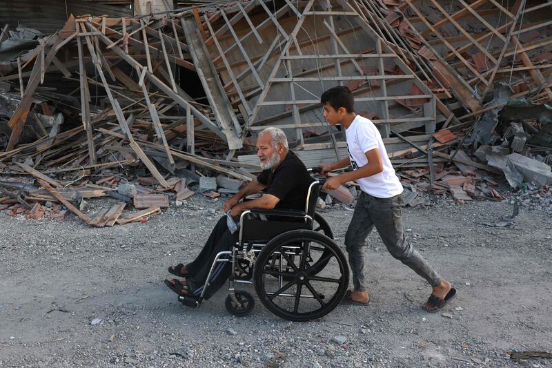 A Palestinian boy pushes a man on a wheelchair past debris in Rafah. AFP