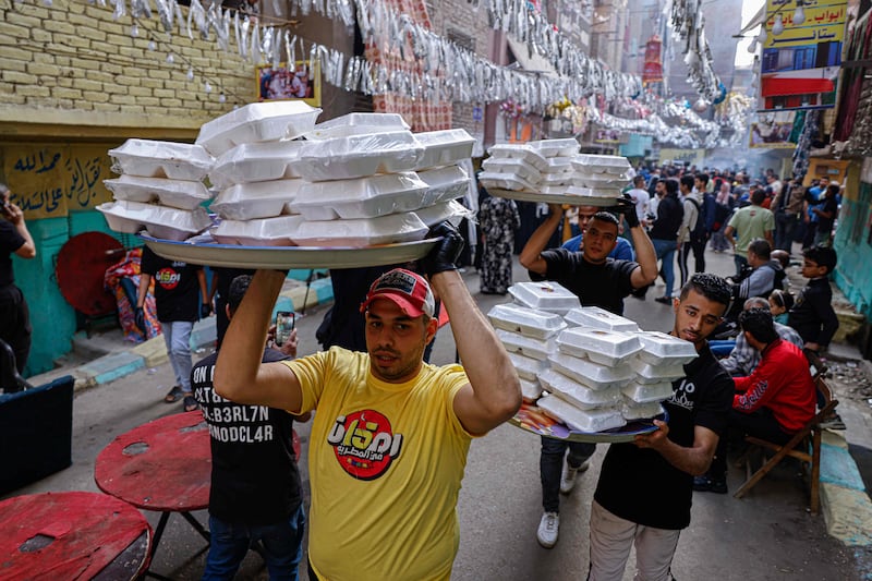 Men distribute meals as Egyptians prepare for the mass iftar 