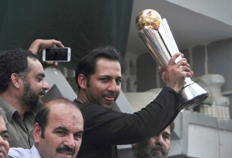 Pakistani cricket team's captain Sarfraz Ahmed raises the Champions Trophy for a crowd gathered to welcome him, outside his residence in Karachi, Pakistan.