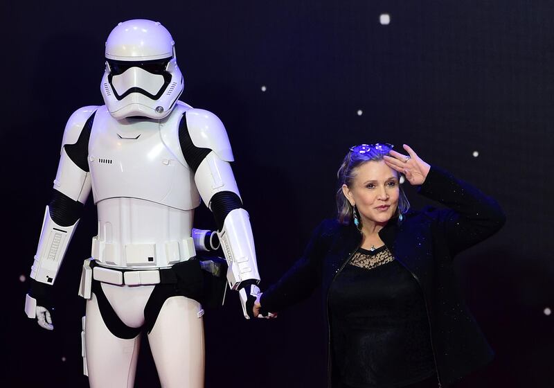 (FILES) In this file photo taken on December 16, 2015 US actress Carrie Fisher (R) poses with a storm trooper as she attends the opening of the European Premiere of "Star Wars: The Force Awakens" in central London. July 27, 2018,"Star Wars: Episode IX" begins filming next week, Disney said Friday, in a shock announcement revealing it will feature both Carrie Fisher in a posthumous appearance and series star Mark Hamill. / AFP / LEON NEAL / TO GO WITH AFP STORY BY FRANKIE TAGGART
