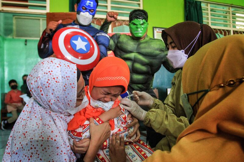 Medical staff dressed in superhero costumes accompany children aged 6 to 11 as they receive a vaccine at a school in Yogyakarta, Indonesia. AFP