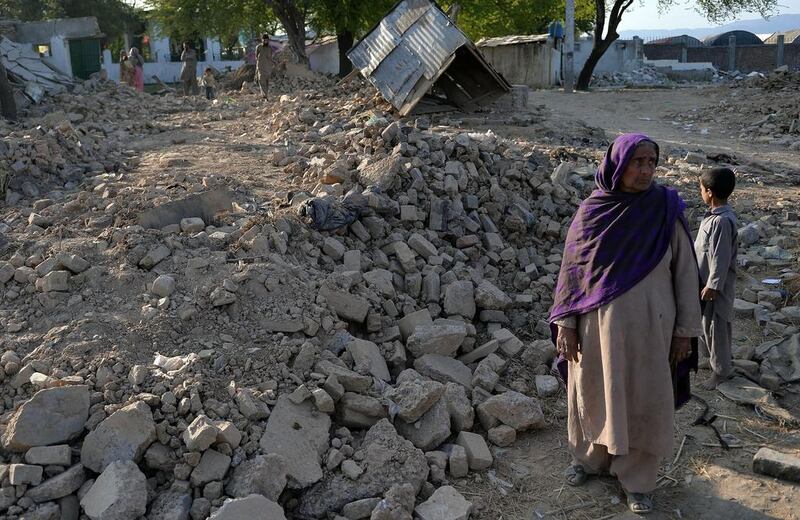 Pakistani woman Mirjan standing in the rubble of her destroyed  house at a slum area of Islamabad. Aamir Qureshi / AFP