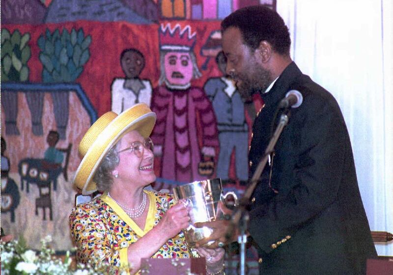 Queen Elizabeth II looks up at Zulu King Zwelithini as he presents her a replica of a cup given to King Cetshwayo by Queen Victoria in 1882, at a luncheon in Durban, South Africa, on March 25, 1995. AFP