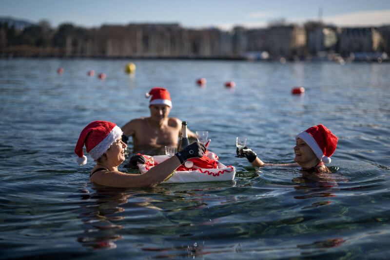 Swimmers wearing Santa Claus hats bathe and have a drink in Geneva Lake. AFP