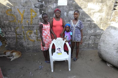 Rachael Fayia, centre, and her children Binta Jalloh, left, Fatmata Jalloh, right, Naomi Dee, second right, pose for a family portrait at their home in West Point, Monrovia, Liberia. The empty chair symbolises Rachael’s husband, who died of the Ebola virus during an outbreak of the disease in 2014.  EPA