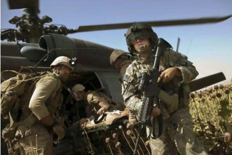 US Army flight medic SPC Daniel Miller, right, stands guard as a wounded colleague is placed in a medevac helicopter at a "hot" landing zone in Sangin, in the volatile Helmand Province of southern Afghanistan, on Friday.