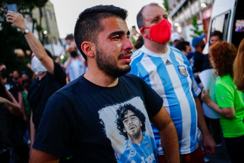 A man wearing a shirt with the face of Maradona cries outside the stadium of the Argentinos Juniors. AP