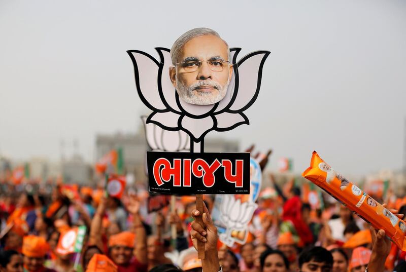 FILE PHOTO: A supporter holds up a cut-out of a lotus, the election symbol of India's ruling Bharatiya Janata party (BJP), with an image of Prime Minister Narendra Modi during a campaign meeting addressed by Modi ahead of Gujarat state assembly election in Kalol on the outskirts of Ahmedabad, India, December 8, 2017. REUTERS/Amit Dave/File photo